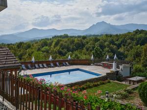 ein Schwimmbad in einem Garten mit Bergen im Hintergrund in der Unterkunft Hotel Tihiat Kat in Aprilzi