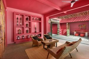 een woonkamer met roze muren en stoelen en een tafel bij PinkCoco Gili Trawangan - Constant Surprises - for Cool Adults Only in Gili Trawangan