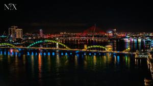 un puente sobre el agua con una ciudad por la noche en HAIAN Riverfront Hotel Da Nang, en Da Nang