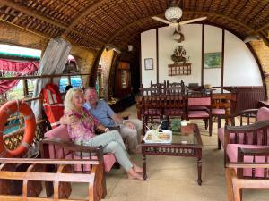 Un uomo e una donna seduti in una stanza di Thara's Houseboat a Alleppey