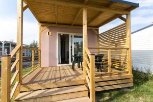 una terraza de madera con pérgola en una casa en Camping Marelago, en Caorle