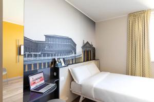 um quarto de hotel com uma cama e um computador portátil numa secretária em B&B Hotel Roma Fiumicino Aeroporto Fiera 1 em Fiumicino