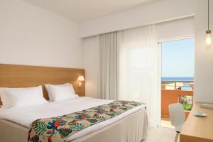 a hotel room with a bed and a large window at High Beach Resort in Malia