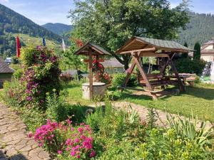 un gazebo in legno in un giardino fiorito di Котедж Зумера a Krivorovnya