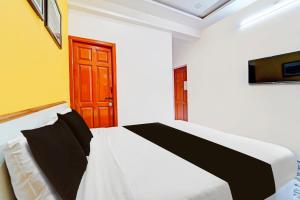 1 dormitorio con 1 cama y puerta de madera en Super Hotel O Vijaynagar Road formerly Anmol Peace Stay, en Ooty