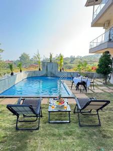 - une piscine avec 2 chaises et une table dans la cour dans l'établissement OCEAN CREST LUXURY VILLA Mahabaleshwar, à Mahabaleshwar