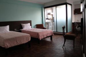 a hotel room with two beds and a chair at Kunan Hotel in Cochabamba