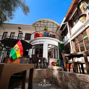 een gebouw met een patio met stoelen en een parasol bij La Culta HOSTAL & CASA CULTURAL in Sucre