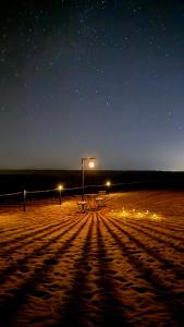 un banco sentado en la playa por la noche en La Duna Desert Camp, en Shāhiq