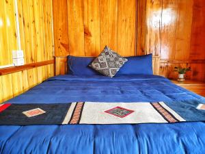 a bed in a wooden room with a blue comforter at Peace Home in Sa Pa