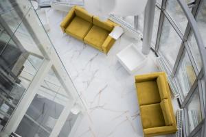 an overhead view of a lobby with yellow chairs and tables at Suncity Hotel & SPA in Šiauliai