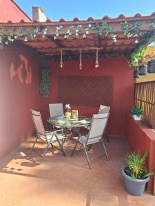 un patio con mesa y sillas en una pared roja en Finca Esther, en Las Palmas de Gran Canaria