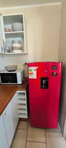 a red refrigerator in a kitchen next to a microwave at Paz natural, Playa, bosque, el descanso ideal in El Tabo