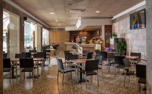 un restaurante con mesas y sillas y un bar en Hotel la Palmera & Spa en Lloret de Mar