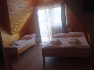 Cette chambre en bois comprend 2 lits jumeaux et des fenêtres. dans l'établissement Tatrzańska Rezydencja pod Brzyzkiem, à Zakopane