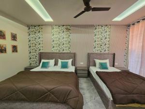 1 dormitorio con 2 camas y ventilador de techo en Zipcode Stay, en Agra