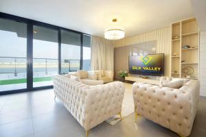 uma sala de estar com cadeiras de couro branco e uma televisão em Silk Valley - Gorgeous 4b Maid Near Al Hamriyah em Sharjah