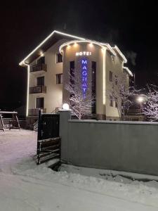 Un edificio con un cartello blu sulla neve di Hotel Magnati Bakuriani a Bakuriani