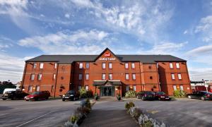 un grande edificio in mattoni con auto parcheggiate in un parcheggio di The Dolby Hotel Liverpool - Free city centre parking a Liverpool