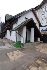 a white building with a green courtyard in front of it at Proskurov Holiday Home in Bukovel