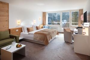 a bedroom with a bed and a living room at Hotel Waldegg - Adults only in Engelberg