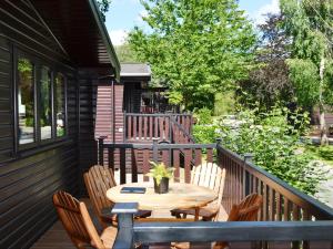 een houten terras met een tafel en stoelen bij Fern Lodge- Burnside Park in Keswick