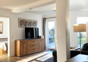 een woonkamer met een flatscreen-tv op een houten dressoir bij Greenhouse Living Apartment Nivis mit Garten - 7 Minuten nach Winterberg - 4 Minuten zur Skipiste in Medebach