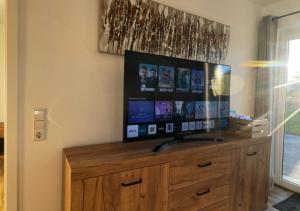 een flatscreen-tv op een houten dressoir bij Greenhouse Living Apartment Nivis mit Garten - 7 Minuten nach Winterberg - 4 Minuten zur Skipiste in Medebach