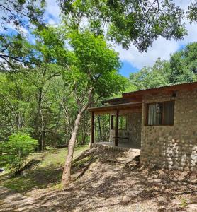 uma casa de pedra com uma árvore em frente em Las Casitas de Piedra I em Villa General Belgrano