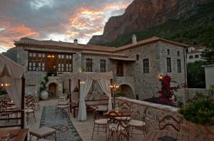 a building with tables and chairs in front of it at Archontiko Hatzipanayioti in Leonidion