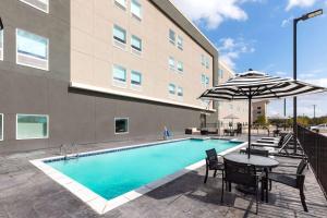 - une piscine avec une table et un parasol à côté d'un bâtiment dans l'établissement La Quinta Inn & Suites by Wyndham Austin Parmer Tech Ridge, à Austin