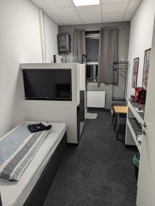 a room with a bed and a flat screen tv at Business-Motel, free XL-Parking, WiFi, massage-chairs, sauna, shared kitchen, breakfast 2go, free soda, coffee in Heimsheim