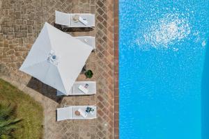 uma vista superior de uma piscina com guarda-sóis brancos em Agri Resort San Giuliano em Santa Maria la Palma