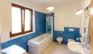 uma casa de banho com azulejos azuis, uma banheira e um WC. em Agri Resort San Giuliano em Santa Maria la Palma