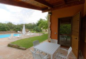 um pátio com uma mesa e cadeiras e uma piscina em Agri Resort San Giuliano em Santa Maria la Palma