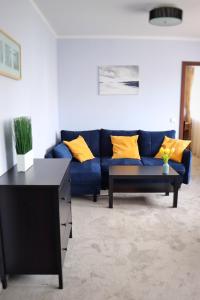 a blue couch with yellow pillows in a living room at Hotel Alpex in Zabrze