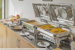 a kitchen counter with several trays of food at Treebo Tranquil Heights in Kodaikānāl