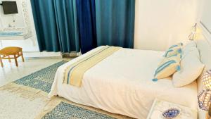 Schlafzimmer mit einem Bett mit blauen Vorhängen in der Unterkunft Dar Henani in Monastir