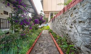 a garden with purple flowers next to a stone wall at Treebo Tranquil Heights in Kodaikānāl