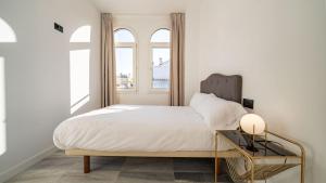 a bedroom with a bed and two windows at William Martin Apartments in Huelva