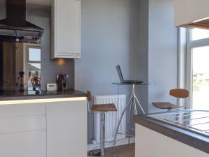 une cuisine avec des placards blancs et un comptoir avec des tabourets dans l'établissement Inver House Apartment, à Inverurie