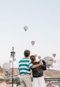 um homem e uma mulher a olhar para balões de ar quente em Turan Cappadocia Cave em Goreme