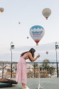 Uma mulher de vestido rosa a olhar para um balão de ar quente. em Turan Cappadocia Cave em Goreme