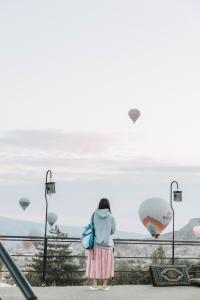 uma mulher olhando para o oceano com balões de ar quente em Turan Cappadocia Cave em Goreme