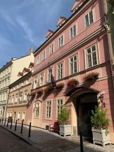 un edificio rosa con piante in vaso di fronte ad esso di Hotel Residence Agnes a Praga