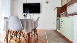 uma cozinha com uma mesa com cadeiras brancas e uma televisão em Apartment Korni em Biograd na Moru