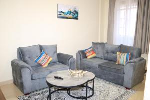 ein Wohnzimmer mit 2 Sofas und einem Couchtisch in der Unterkunft Texas Homes Meru 1 and 2 Bedroom Apartments in Meru