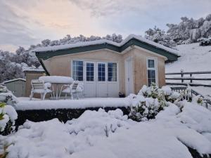 une maison avec une table et des chaises dans la neige dans l'établissement Roberts’ Cottage, à Westport