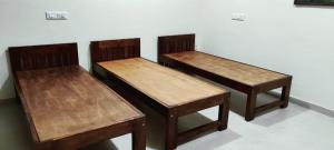 three wooden benches sitting next to a wall at Malnad Bliss in Sringeri