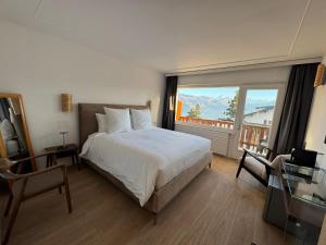 1 dormitorio con cama y ventana grande en Crans Montana Suites, en Crans-Montana